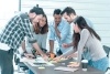 Diverse team standing around a table working