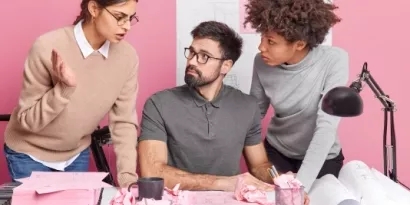 Three people talking to each other in a pink office