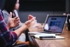 A closeup of a person talking with their hands in front of their computer.